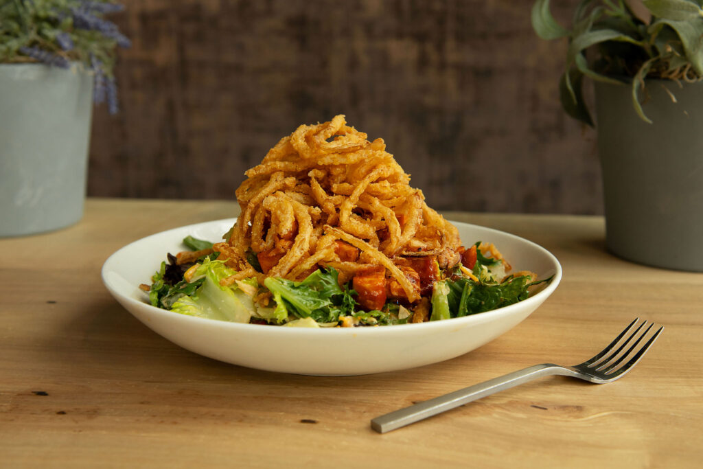 BBQ Chicken Salad - Mixed lettuce, bbq chicken, charred corn, bacon, pickled red onion, black beans, cheddar and pepper jack tossed in a bbq ranch dressing and topped with fried onion strings