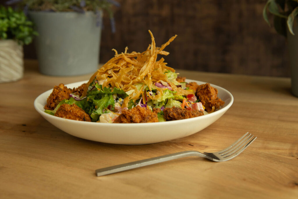 The Southern Salad - Southern fried chicken, tomato, roasted corn, black beans, tortilla strips and pepper jack cheese tossed in creamy chipotle ranch