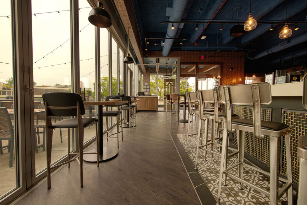 Main bar space with floor to ceiling retractable doors, TVs, and multiple seating arrangements at Fatpour Lincolnwood