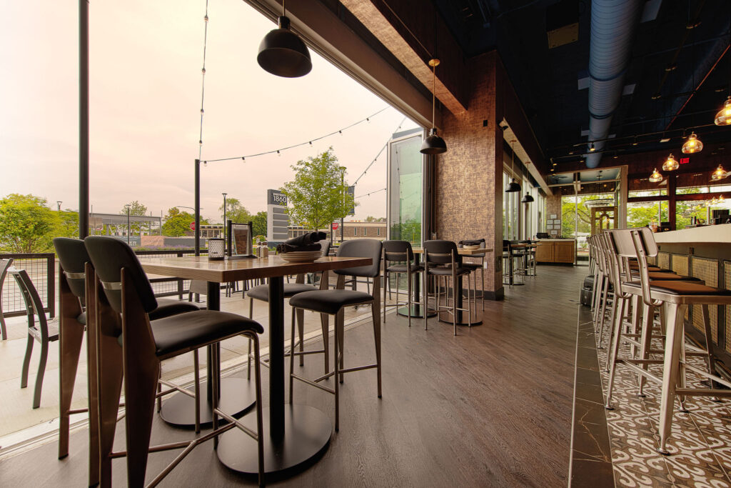 Main bar space with floor to ceiling retractable doors, TVs, and multiple seating arrangements at Fatpour Lincolnwood