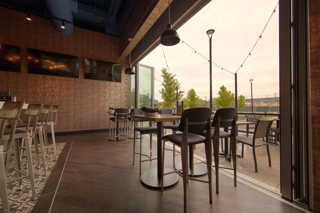 Main bar space with floor to ceiling retractable doors, TVs, and multiple seating arrangements at Fatpour Lincolnwood