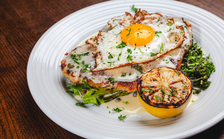 Pank Crusted Swordfish with lightly breaded swordfish, char grilled broccolini, fried egg, lemon caper butter sauce